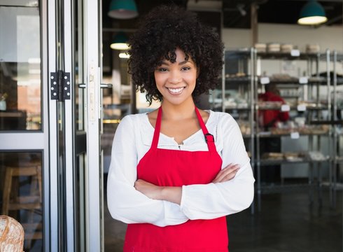 Pretty server in red apron with arms crossed - Powered by Adobe