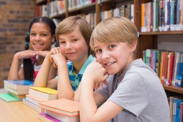 Cute pupils looking at camera in library