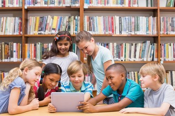 Fototapeta na wymiar Cute pupils using tablet computer in library