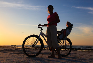 Fototapeta premium Silhouette of mother and baby biking at sunset