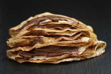 thin crepes or blinis with chocolate cream on slate board
