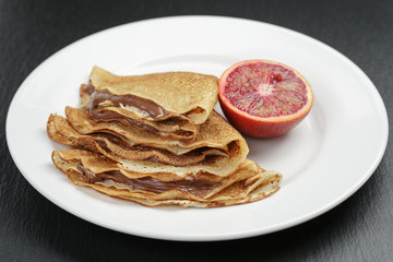 thin crepes or blinis with chocolate cream on plate