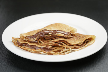 thin crepes or blinis with chocolate cream on plate