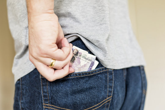 Man puts cash bank notes into back pocket of jeans