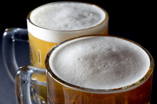 Closeup of Fresh Beer with Foam  in Two Beer Glasses On Black