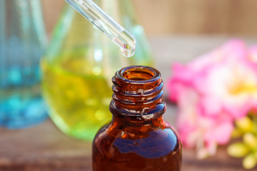 drop of oil dripping from pipette into bottles of essential oil