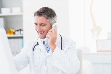 Male doctor using landline phone