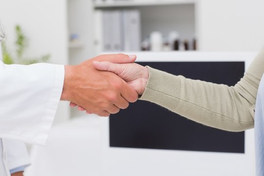 Male doctor and female patient shaking hands