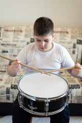 Fototapeta na wymiar Boy teenager playing drums in room
