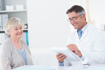 Fototapeta premium Doctor writing prescriptions for senior patient