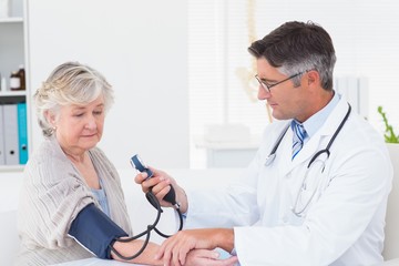 Doctor checking female patients blood pressure