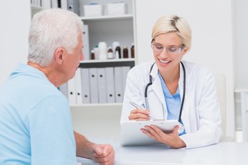 Fototapeta premium Doctor writing prescription for senior man