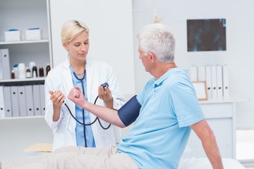 Doctor checking senior mans blood pressure