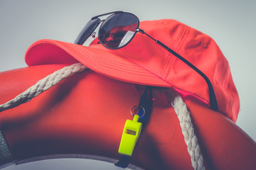 Hat glasses whistle and lifesaver Lifeguard equipment Summer safety concept - obrazy, fototapety, plakaty