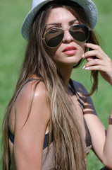 Woman on grass with hat and sunglasses on bright sunny day