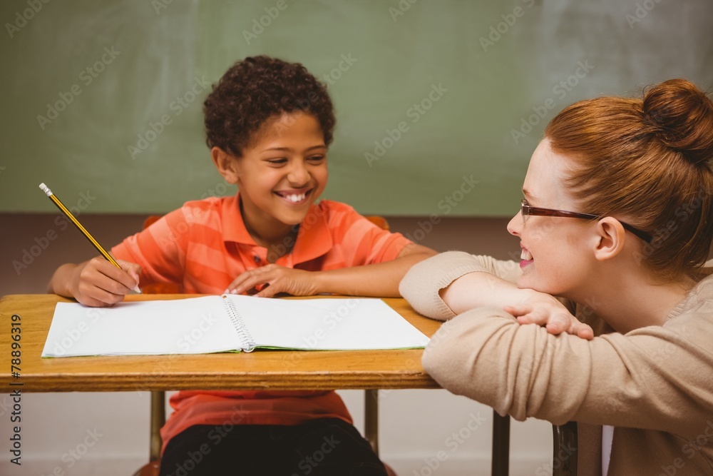 Poster teacher assisting boy with homework in classroom