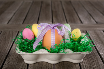 Ei mit einer Schleife als Geschenk in einem Osternest/Eierkarton