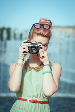 Beautiful girl in vintage clothing making picture with retro cam