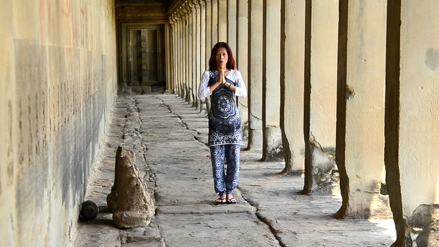 Zoom Out of Female Buddhist with Hands in Prayer in Temple Hallway  - Angkor Wat Temple Cambodia