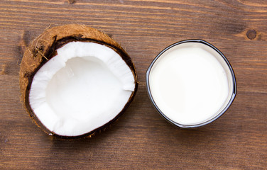Glass with coconut milk on wooden table seen from above