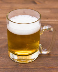 Mug of beer with foam on wooden table