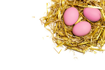 pink eggs in a nest of straw isolated on white background
