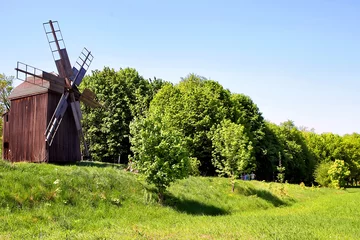 Fotobehang Molens Oude windmolen op een heuvel in een veld. Tegen de achtergrond van