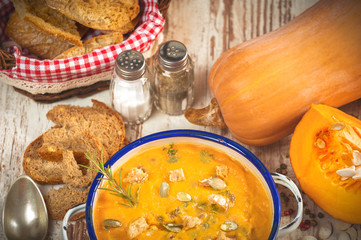 Homemade pumpkin soup in a tin bowl on rustic table