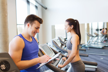 Fototapeta na wymiar happy woman with trainer on treadmill in gym