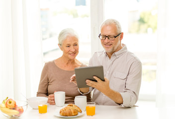 happy senior couple with tablet pc at home