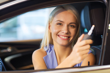 happy woman getting car key in auto show or salon