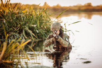Soldier moving through the water and aiming at the enemy