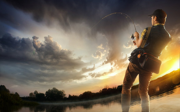 Young man fishing at dramatic sunset