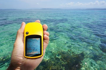 Rolgordijnen Hand holding a marine GPS navigator over the sea © dam