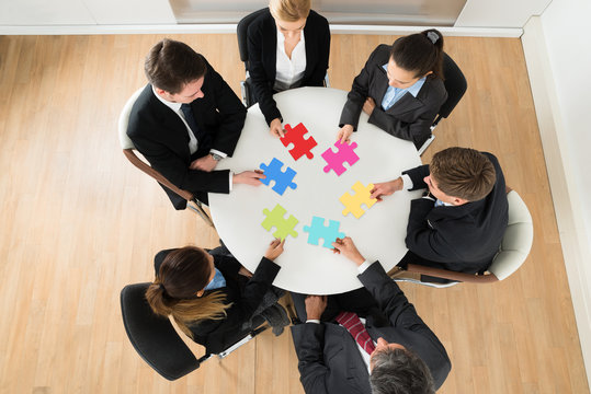 Businesspeople Holding Multi-colored Jigsaw Puzzle