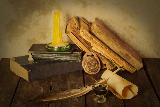 Old books, candle and feather amulet with ink