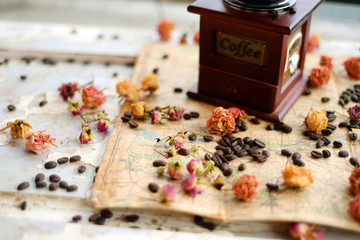Coffee beans and dried roses scattered upon the old map