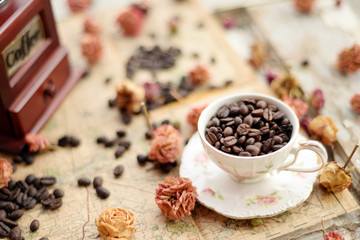 Coffee beans and dried roses scattered upon the old map