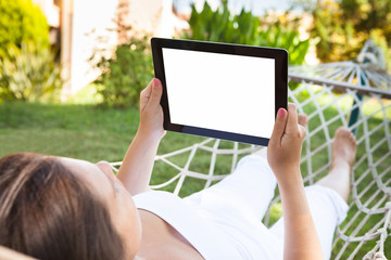 Woman Using Digital Tablet In Hammock At Park