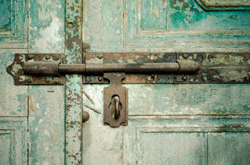 Rusted keyhole on green wooden door