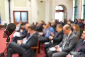 Microphone in focus against blurred audience