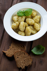 Glass plate with gnocchi served with basil pesto, close-up