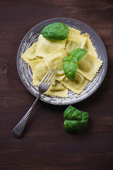 Ravioli with green basil over dark wooden background, above view