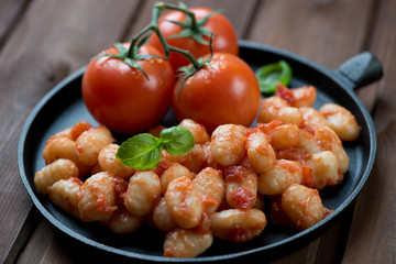 Frying pan with gnocchi in tomato sauce, selective focus