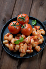 Italian gnocchi with tomato sauce and green basil in a pan