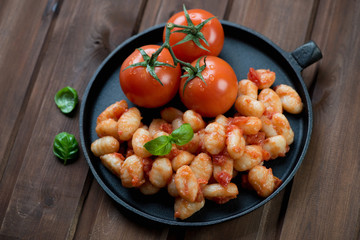 Italian gnocchi with tomato sauce on a dark wooden background