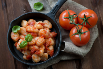 Frying pan with gnocchi in tomato sauce, view from above