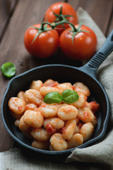 Frying pan with gnocchi in tomato sauce, selective focus
