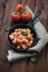Gnocchi with tomato sauce and basil in a frying pan, studio shot