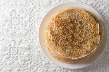 Plate with homemade yeast pancakes on a lace tablecloth